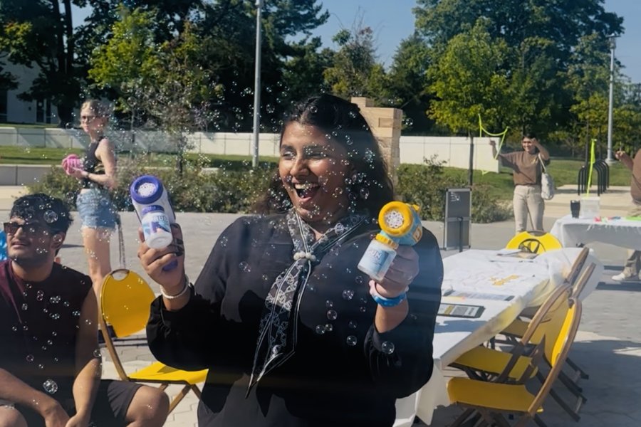 International student from India, Trivedi, stands for photo while making bubbles. 