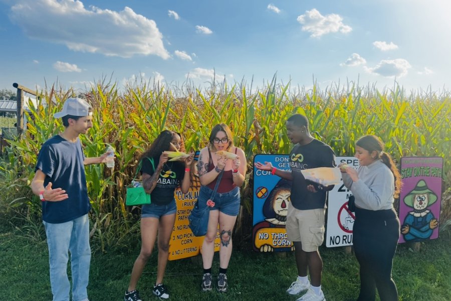 International student from India, Trivedi, stands for photo with WMU students in front of corn field. 