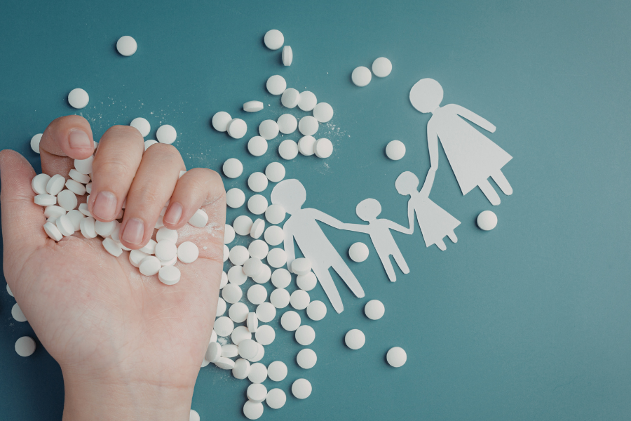 Hand full of pills and paper cutout of family