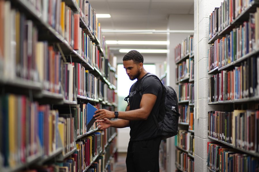 Student standing in the stacks at Waldo Library looking at a map.