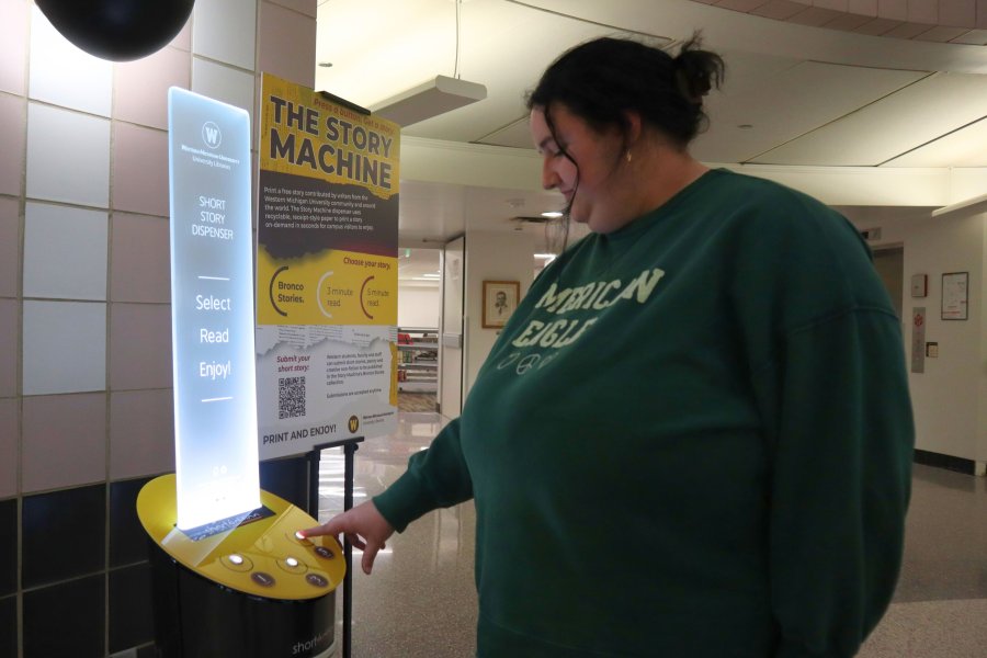A student presses a button on the Story Machine in Waldo Library.