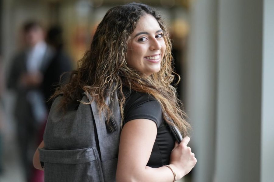 A WMU student walking in a hallway smiling at a camera.