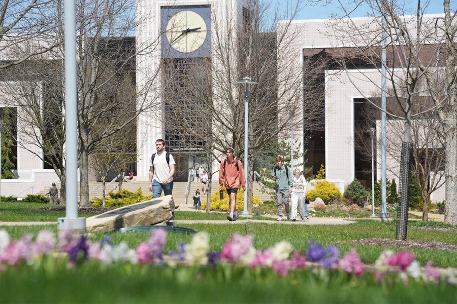 Students walk outside on campus in front of Waldo Library on a spring day.