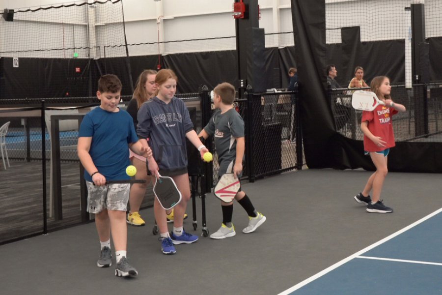 Kids lined up a the Pickleball serving line waiting to practice servering.