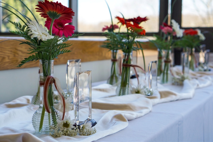 A row of glass award trophys on a table draped with flowing white fabric, set for the award ceremony.