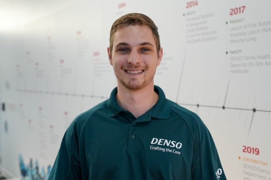 WMU Alum Cory Scholler, a brunette man wearing a green collared shirt standing in front of a whiteboard. 