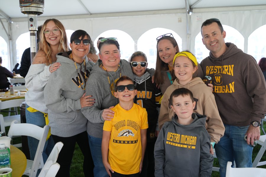 A large family wearing WMU spirit wear in a big white tent.