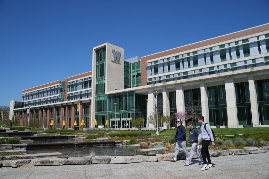 Students walk by Sangren Hall on a sunny day.
