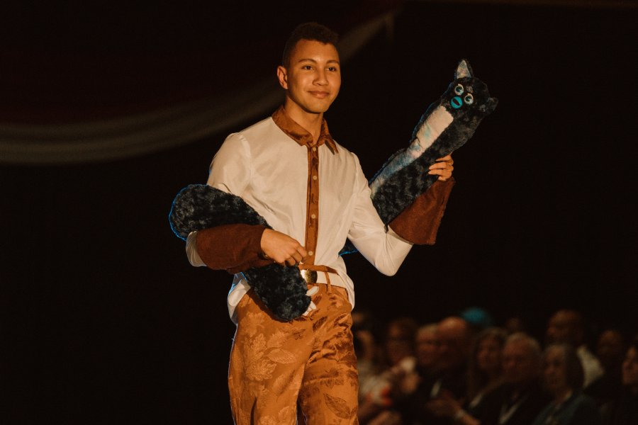Male student poses at the end of the runway during MODA's 2025 fashion show