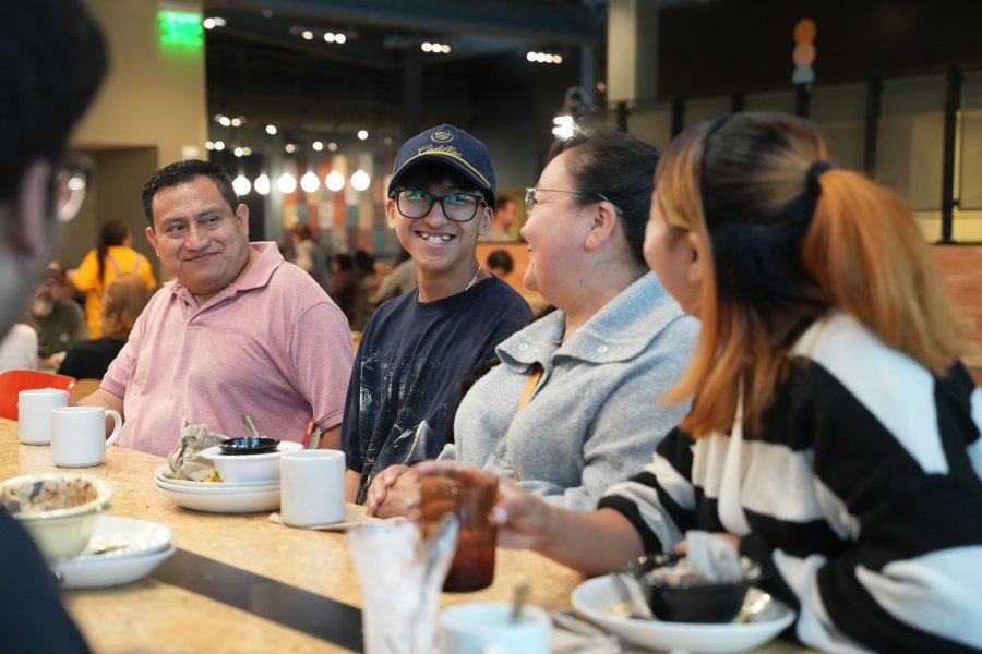A WMU student smiling at their family members while eating breakfast in the Valley Dining Center.
