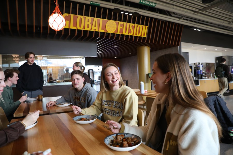 WMU students sitting at a table and eating food from the Global Fusion venue in the Student Center.