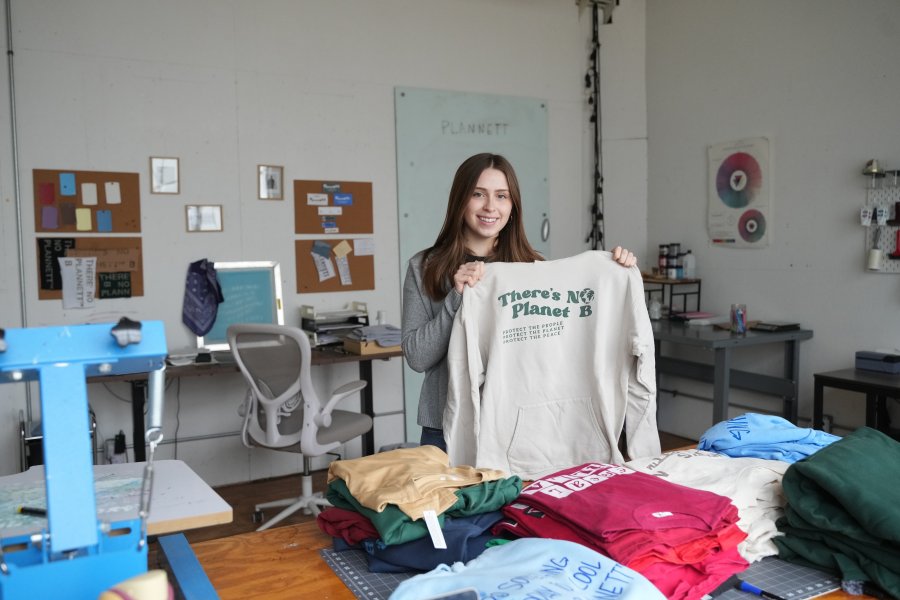 Julia Adams holds up a t-shirt inside Plannett Gunnett's downtown Kalamazoo fashion studio.