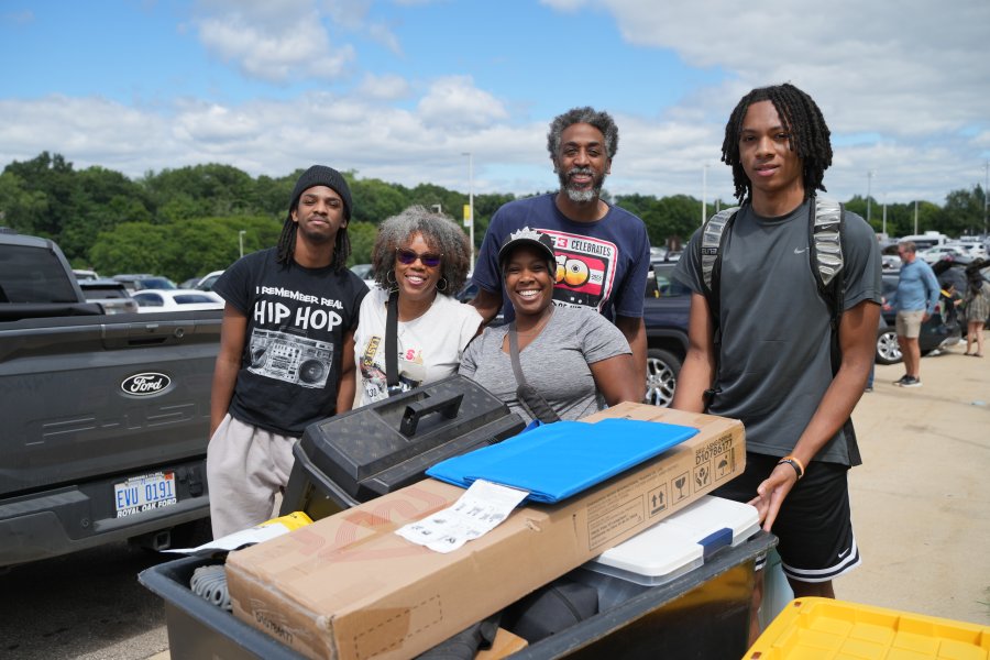 A group photo of a smiling family with their WMU student beside a full move-in cart. 