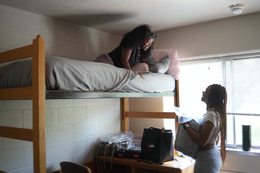 One student in a loft bed looks down at their roommate on move in day.