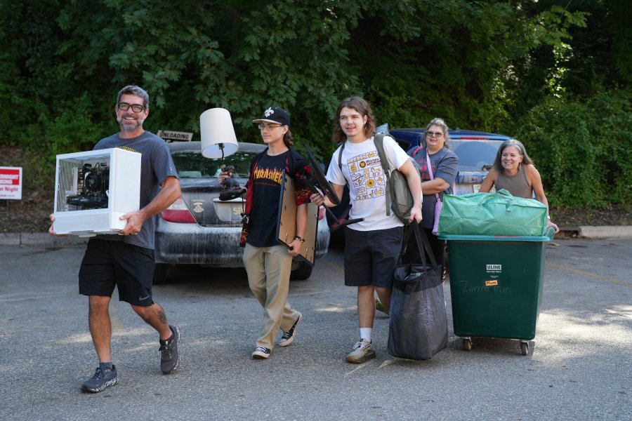 A family carries a student's belongings into a residence hall on move in day.