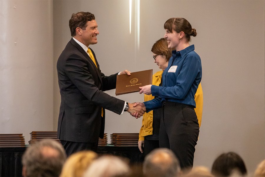President Russ Kavalhuna gives student Erica MacQueen an award for being the Presidential Scholar in biological sciences.