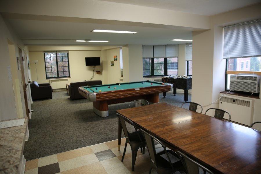 A large room with lounge furniture, a TV, and a pool table.