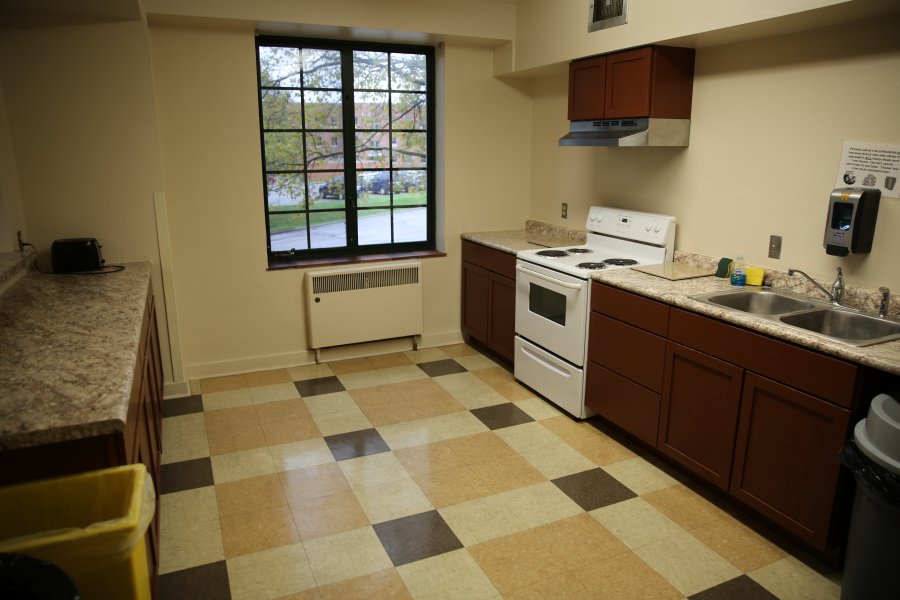 A spacious community kitchen with an oven and a stove.