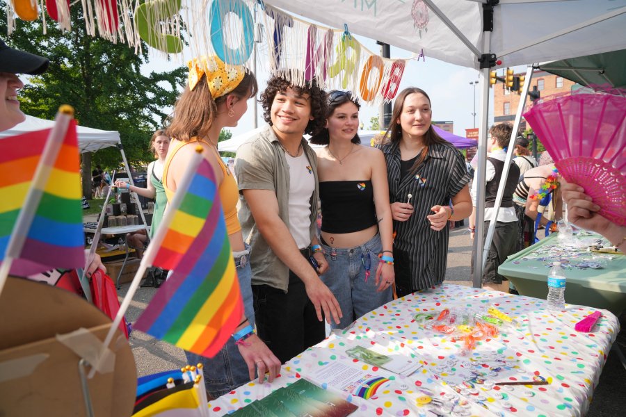 Four students visit a table at the Kalamazoo Pride event in downtown Kalamazoo. 