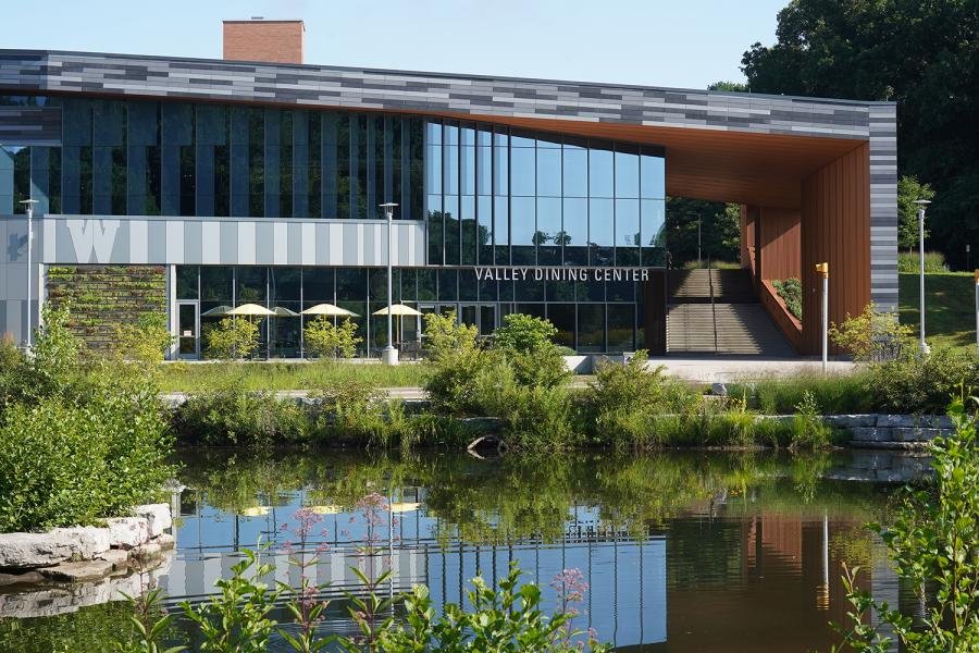 A modern brick and glass building bordered by Goldsworth Valley pond.