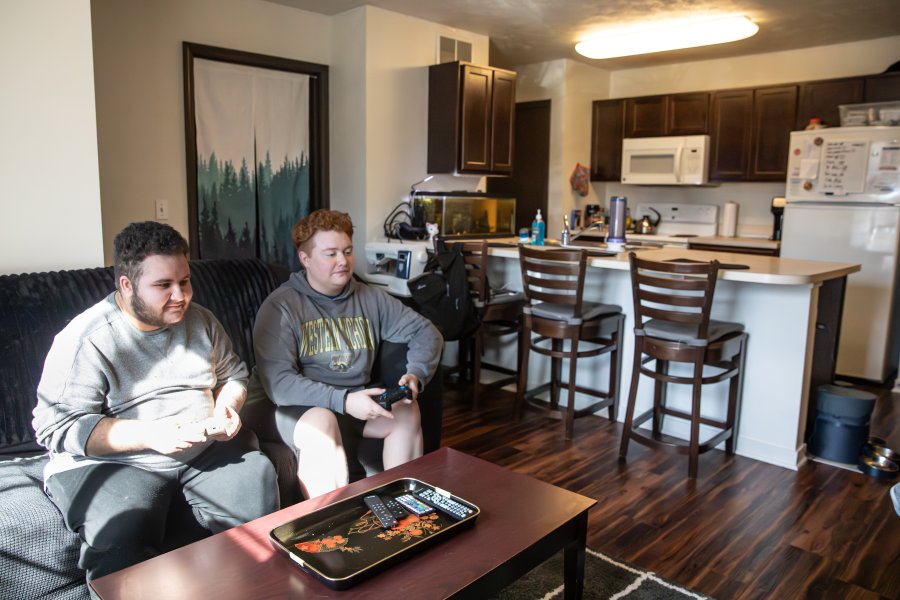 Two roommates playing videogames in the living room of their Western View apartment.
