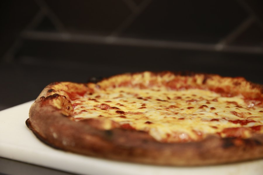 A freshly-made cheese pizza sitting on a white cutting board.