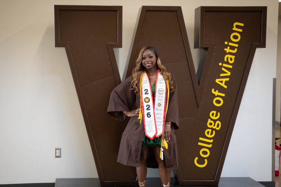 A'maree Waddell stands in front of a large W sculpture at the College of Aviation.