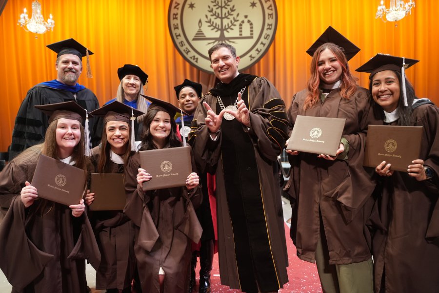 President Russ Kavalhuna with fall 2025 graduates on the Miller Auditorium stage.