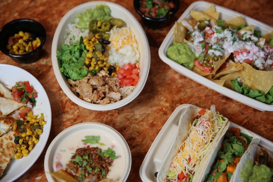 A display of dishes available at Fuego Verde, including tacos, burrito bowl, nachos, chips and queso.