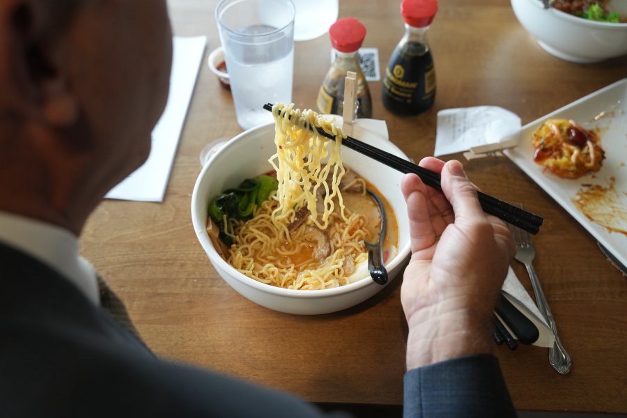 A person eats a bowl of authentic raman with chopsticks.