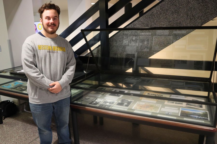 Western Michigan University student Owen Wittbrodt working on exhibit case about Kleinstuck Preserve.