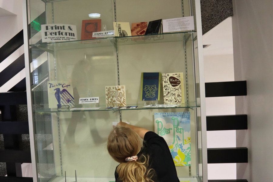 Western Michigan University student Hope Donovan working on exhibit case about 50 years of WMU Theatre graphic design.