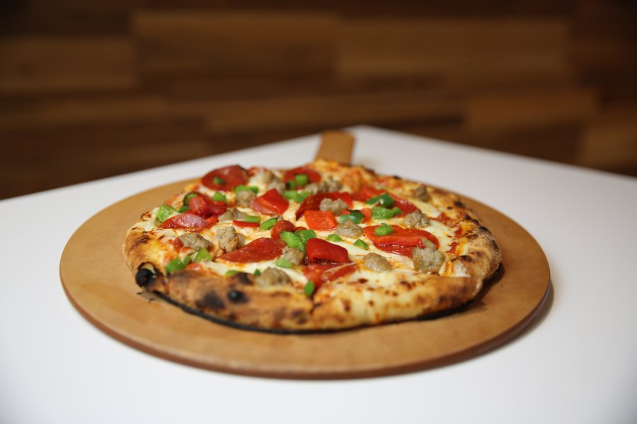 A Bronco Deluxe pizza from My Pie sits on a wooden serving tray.