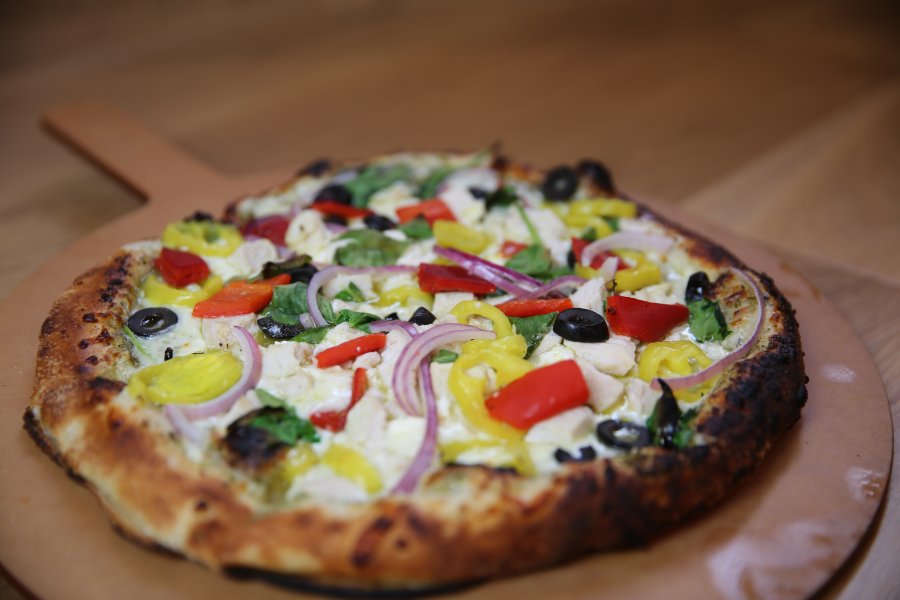 A My Pie greek signature pizza on a wooden serving tray.