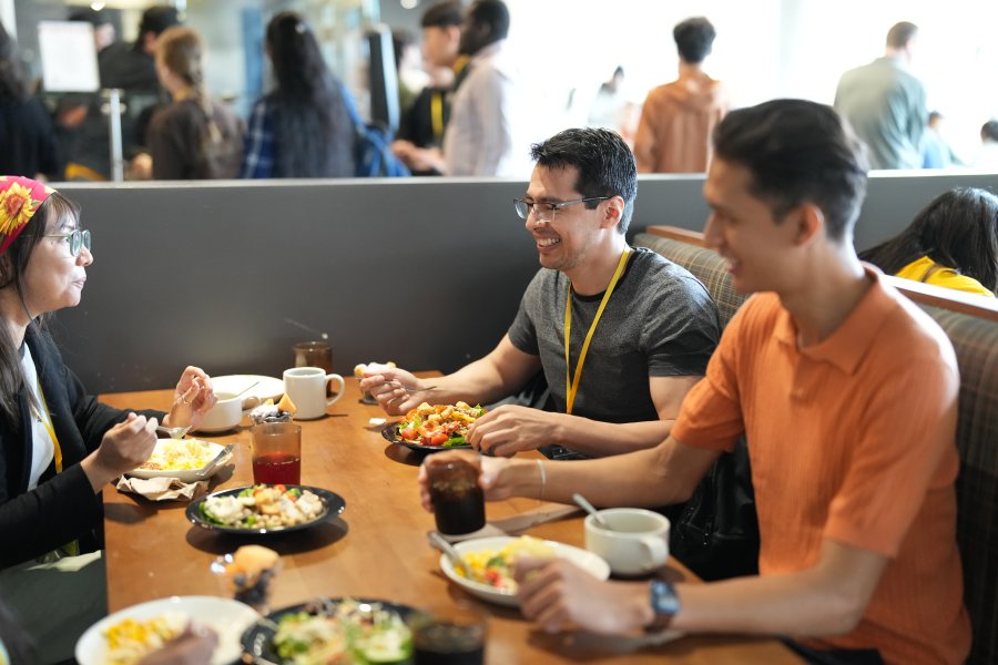 A group of students sitting in a booth enjoying a meal.