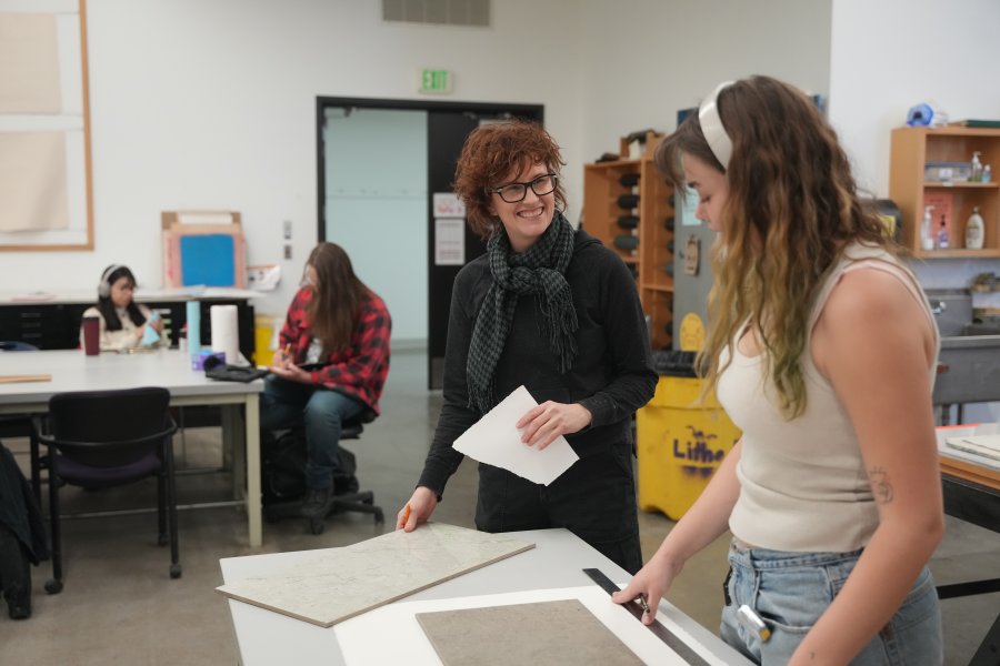 A WMU professor talking to a student in a classroom.