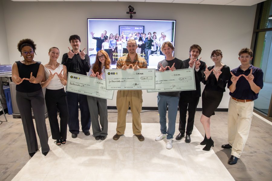 2026 Venture Studio Pitch Event students make the W sign with their fingers and the winners hold their checks.