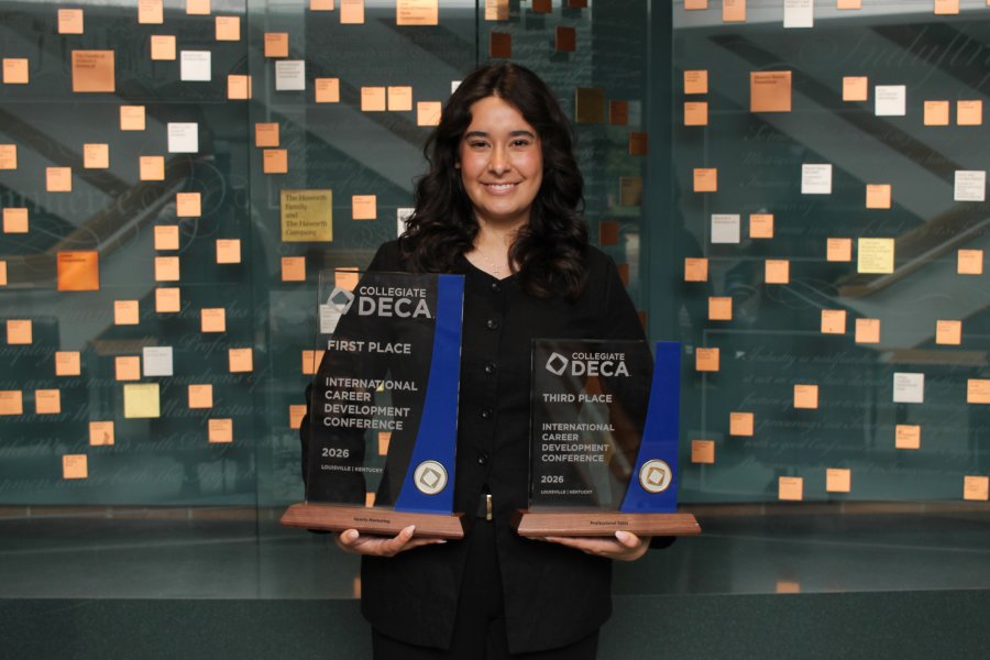 Alexis Ehlebracht holds her first-place and third-place DECA trophies at WMU Haworth