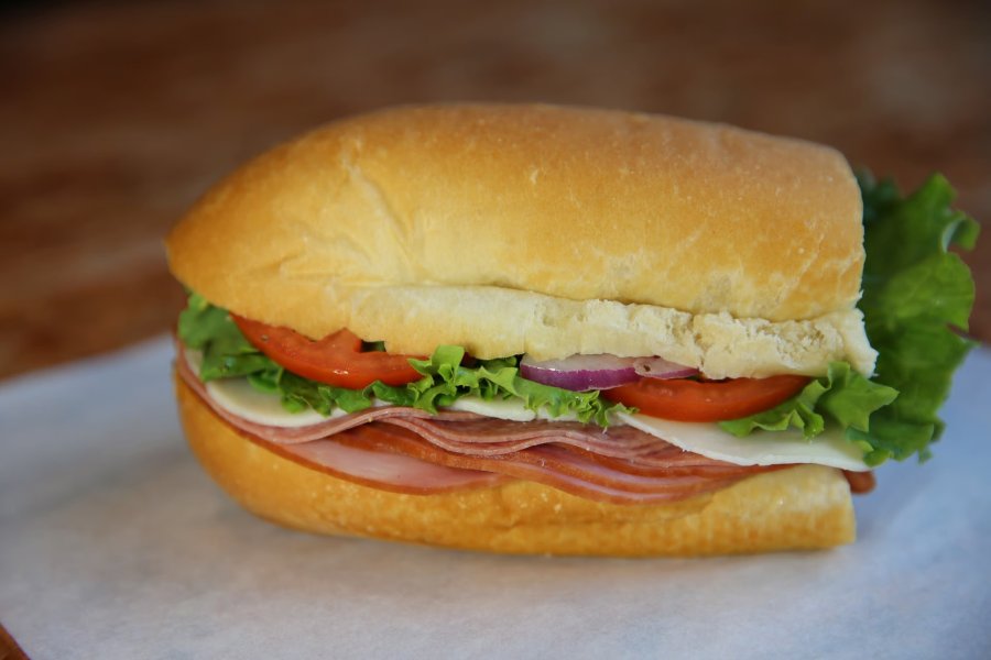 A half-sub sandwich on white bread with meat and vegetables.