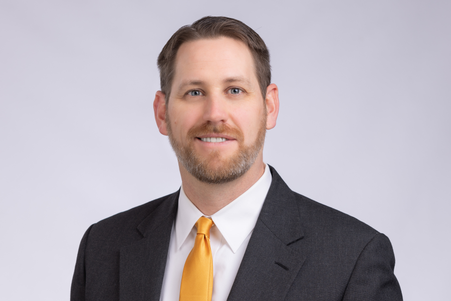 Finance professor Matt Ross wearing a dark suit and yellow tie