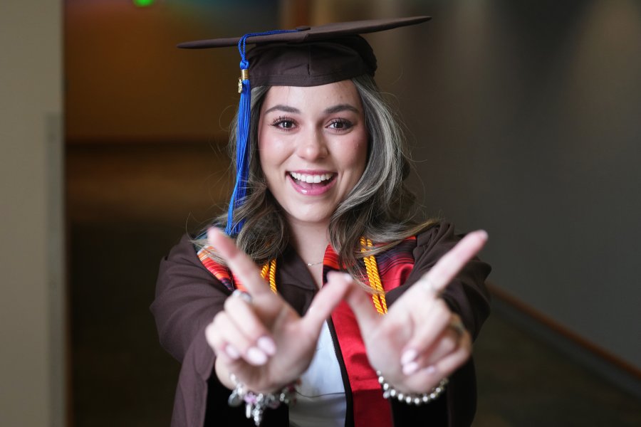Daniela Padilla in her grad clothing holding up the 'W' hand sign
