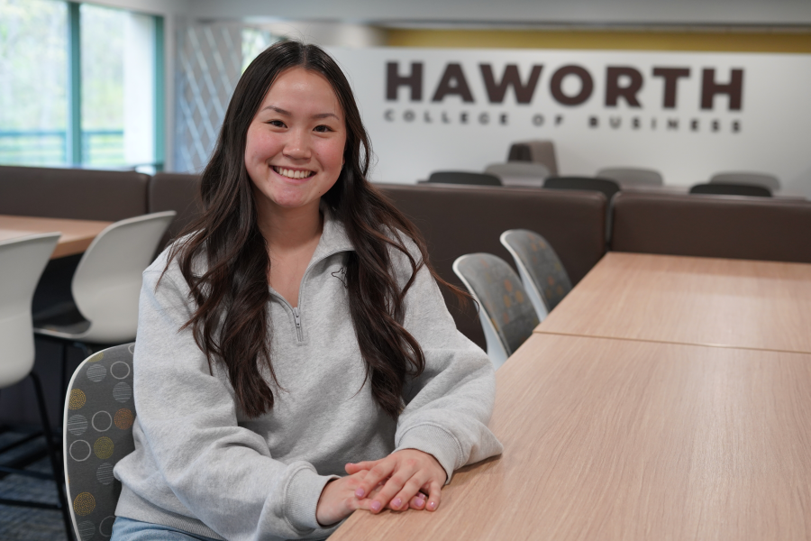 Student sitting at table in front of Haworth Business College sign