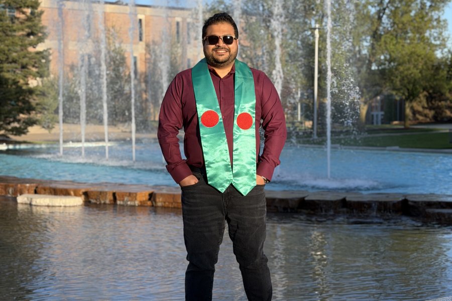 An international student poses wearing the flag of his country during graduation season.