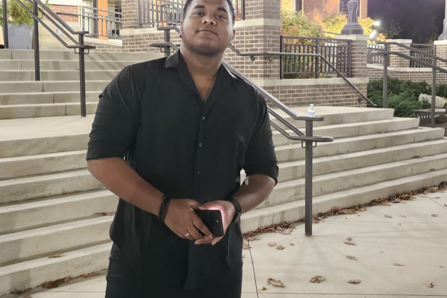 An international student poses on campus during graduation season.