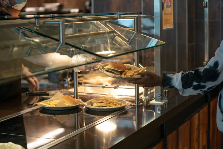 An employee hands a double cheeseburger to a student at Blazin' Bronco, the grill venue at the Valley Dining Center.