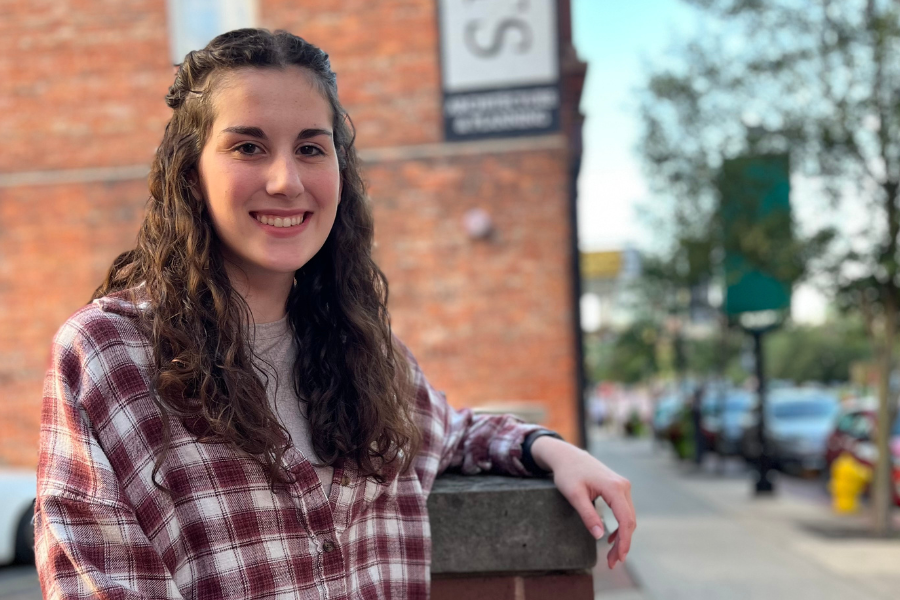 BSW student, Hailee Hamilton sitting outdoors in front of a brick building.