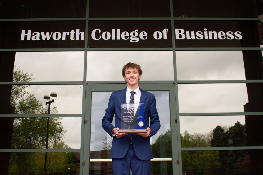 Liam Zoli stands in front of the Haworth College of Business with his third-place DECA plaque