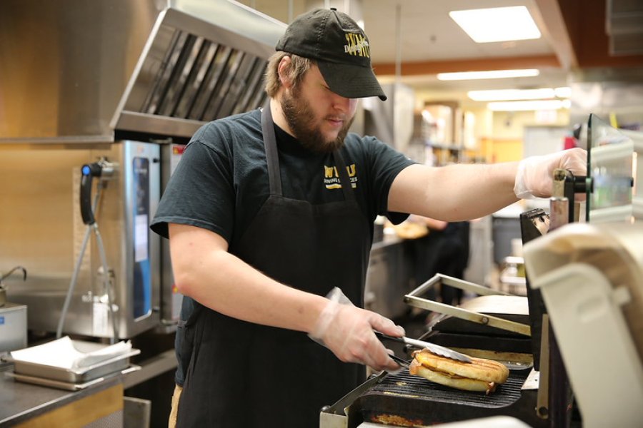 Student employee in Parkview Cafe toasting a panini sandwich for a customer.