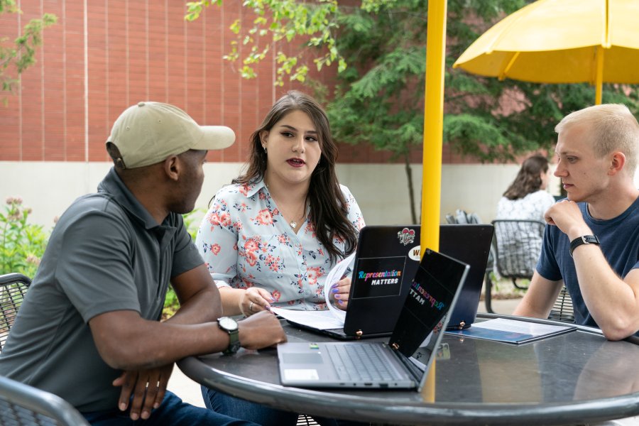 Students gathered at a table outside Parkview Cafe discussing work.
