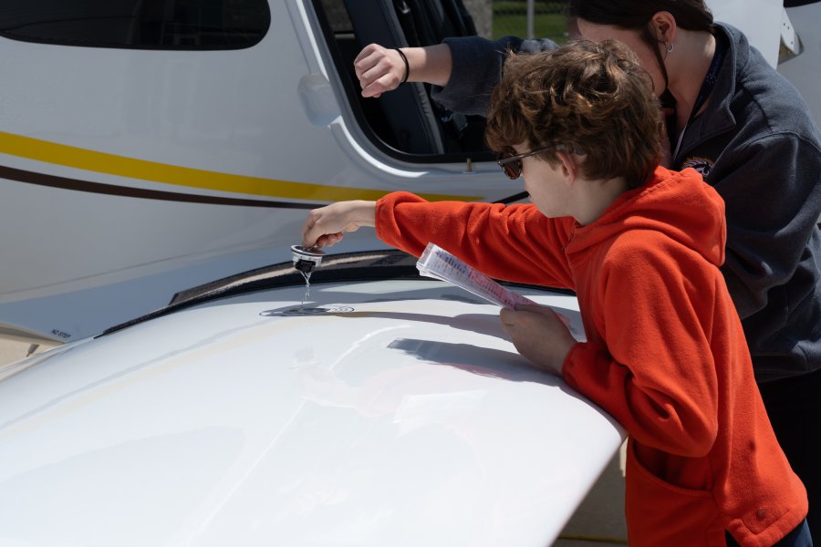 Vail Fear checks fuel in a plane's wing.
